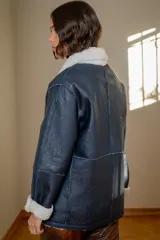 Campera reversible de cuero ovino con interior de piel sintética, diseño oversize, cierre frontal con broches y bolsillos laterales.