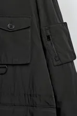 Parka técnica de corte relajado con acabado repelente al agua. Presenta cuello subido con capucha ajustable, cierre frontal con cremallera oculta por solapa con botones y cintura ajustable con cordón. Incluye múltiples bolsillos frontales con solapa, un bolsillo con cremallera en la manga y puños con interior en rib. El diseño cuenta con interior acolchado y aberturas laterales con cremallera en el bajo.