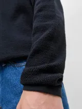 Polo de manga larga con textura estructurada, cuello clásico y cierre frontal de botones. Presenta un corte relajado con hombros caídos.