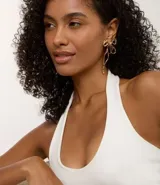 Par de caravanas con diseño de lazo en metal con baño color oro claro. Presentan una estructura calada y acabado texturizado.