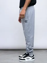 Pantalón de jogging gris melange con puños ajustados en los tobillos y cordón en la cintura. Presenta el logo Umbro bordado en negro en la pierna izquierda.