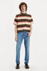 Jean de corte slim fit con tiro medio, confeccionado en denim de tono azul medio con acabado desgastado.