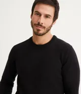 Suéter negro de tejido de punto pesado, con cuello redondo y mangas largas.