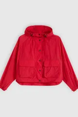 Campera parka roja estilo blouson con capucha ajustable, cierre frontal de botones a presión, bolsillos frontales con solapa y diseño holgado.
