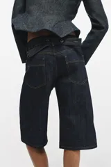 Bermuda de tiro medio confeccionada en denim de algodón, con diseño de cinco bolsillos, trabillas en la cintura y costuras a contraste.