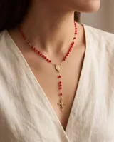 Collar rosario de acero con baño de oro, compuesto por cuentas de cristal rojo y un dije de San Benito con cruz colgante.