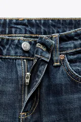 Jeans de mezclilla azul oscuro con efecto lavado, tiro bajo y pierna ancha extra larga. Modelo de cinco bolsillos con cierre frontal de cremallera y botón metálico.