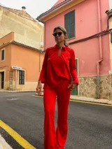 Conjunto de camisa y pantalón rojo con bordado de lunares. La camisa es de manga larga, con cuello polo y abertura en el pecho. El pantalón es de corte acampanado.