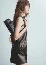Vestido corto de efecto piel con diseño recto y cuello redondo. Presenta un corte sin mangas y cierre de cremallera invisible en la parte posterior.