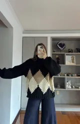 Buzo de tejido de punto grueso con cuello alto, mangas largas abullonadas y diseño de rombos en colores crema, beige y negro.
