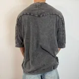 Remera de corte oversize en color verde oliva con efecto de lavado gastado. Presenta cuello redondo, mangas cortas con dobladillo ancho y costuras visibles.