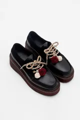 Zapato tipo mocasín de plataforma color bordó, confeccionado en una combinación de cuero liso y gamuza. Presenta cordones bicolores con detalle de borlas decorativas en el empeine.