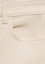 Jeans tiro alto corte mom-fit de algodón elástico, en color beige claro, con cinco bolsillos, trabillas y cierre delantero de cremallera y botón.