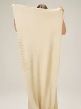 Chal de punto color beige con textura acanalada y sutil brillo metalizado.