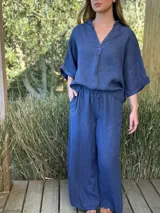 Blusa de lino color blanco, con cuello camisero y escote en V profundo, mangas 3/4 y corte holgado.