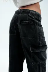 Pantalón cargo de tiro medio confeccionado en denim marrón oscuro. Presenta bolsillos laterales con solapa, bolsillos clásicos y un cinturón integrado del mismo tejido con hebilla metálica.