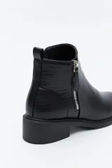 Bota corta de cuero sintético color negro, con taco bajo cuadrado y cierre lateral metálico. Presenta un detalle texturizado tipo reptil en la parte posterior del talón.