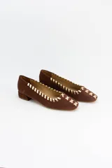Mocasines de gamuza negra con detalle de costuras cruzadas en tono bronce a lo largo del borde y en la puntera. Poseen un taco bajo cuadrado de 2 cm.