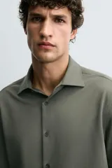 Camisa de corte regular fit color celeste, confeccionada en tejido fácil de planchar. Cuenta con cuello italiano abierto, manga larga con puño abotonado y cierre frontal con botonadura.