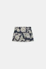 Falda pantalón corta de color azul marino con diseño bordado de flores en hilo crudo, forro interior y cierre lateral con cremallera oculta.