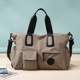 Bolso deportivo multifunción color negro, con diseño liso, compartimento principal con cierre, bolsillo frontal con solapa y bolsillo frontal con cierre. Cuenta con doble asa de mano y correa de hombro ajustable y extraíble. Incluye detalle de logo circular en la parte inferior.
