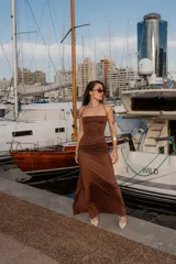 Vestido largo color marrón chocolate, con breteles finos, escote recto y fruncido lateral. Presenta un tajo lateral en la falda.