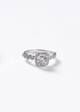 Anillo de plata 925 con diseño Lady Di, presenta una zirconia central de corte brillante rodeada por un halo de pequeñas piedras, con banda decorada con zirconias adicionales.