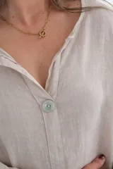 Blusa color crudo de lino con corte holgado, mangas 3/4 y cuello en V con botón.