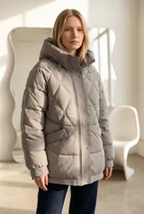 Campera acolchada color gris con diseño de rombos, capucha integrada, cierre frontal con botones a presión y bolsillos laterales. Presenta puños y ruedo con terminación acanalada.