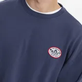 Buzo de cuello redondo color gris melange, con diseño de calce holgado y logo circular de la marca Reef estampado en el pecho.