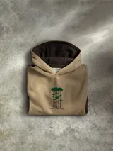 Buzo con capucha tipo canguro en color beige con paneles laterales en color marrón oscuro. Presenta un diseño bordado central de árboles y detalles gráficos en las mangas. Incluye bolsillo frontal tipo canguro, capucha forrada y puños acanalados.