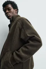 Sudadera de corte relajado confeccionada en tejido con efecto borreguillo, con cuello subido, cierre frontal de cremallera y bolsillos de vivo en la cadera. Presenta mangas largas con puños elásticos y acabados con cinta elástica.