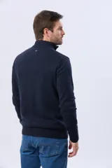 Buzo tejido liso de algodón color beige, con cuello alto, cierre frontal parcial y detalle de tirador en cuero.