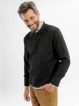 Buzo de tejido de punto en color negro, con cuello tipo polo y cierre frontal parcial. Presenta puños y ruedo acanalados.