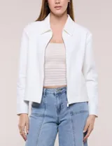 Camperita corta blanca de punto elastizado, con cuello camisero, cierre frontal completo y mangas largas con puños anchos abotonados.