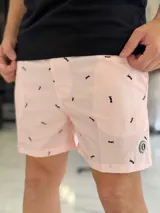 Short de baño rosado con estampado de pequeños motivos negros, corte corto y cordón ajustable en la cintura.