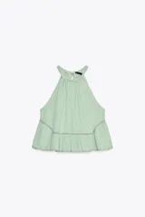 Top de gasa color menta con cuello halter y lazada posterior. Presenta detalles de bordados calados a tono y un bajo con terminación en volante.