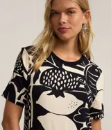 Vestido corto de corte recto estilo camiseta, con cuello redondo y mangas cortas. Presenta un estampado gráfico en blanco y negro con motivos de frutas (limones, granadas) y peces.