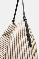 Bolso tipo shopper de tejido con diseño de cuadros en tonos verdes, blancos y marrones, decorado con apliques brillantes. Cuenta con asa de hombro ajustable en material sintético negro, cierre mediante botón imantado y bolsillo interior con cremallera.