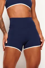 Short deportivo azul marino de cintura alta, con detalles de ribetes en color blanco en los laterales y en el contorno del ruedo.
