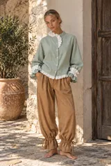 Pantalón azul deslizante de corte ancho, con cintura elástica y puños fruncidos ajustables mediante tiras atadas en los tobillos.