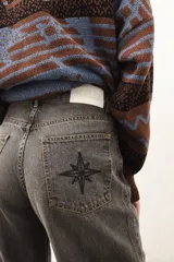 Jean de corte recto y largo, de tiro medio, color gris oscuro con efecto lavado. Presenta un bordado de estrella en los bolsillos traseros.