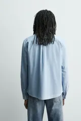 Camisa de corte regular confeccionada en tejido de algodón con efecto lavado. Presenta cuello solapa, manga larga con puños abotonados, cierre frontal de botones y dos bolsillos de plastrón con solapa en el pecho.