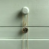 Collar de cadena fina dorada con dije principal circular con relieve y cristales incrustados, acompañado de dijes colgantes de luna creciente y estrella, también con cristales.