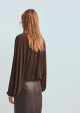 Blusa de color marrón chocolate con cuello redondo, diseño fruncido en la parte superior y mangas largas abullonadas con puños elásticos.