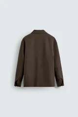 Chaquetón de corte regular fit, con cuello solapa, manga larga y cierre frontal con botones. Presenta dos bolsillos de plastrón con solapa en la parte frontal y un bolsillo interior.