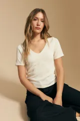 Remera de manga corta confeccionada en tejido acanalado, con escote en V y detalles de puntilla en el borde del escote y las mangas. Presenta un corte ajustado al cuerpo.