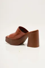 Zapato de plataforma tipo sueco, de empeine amplio en ante, con plataforma alta y taco ancho. Puntera cuadrada y diseño abierto en el talón.