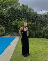 Vestido largo con estampado tie-dye en tonos violeta y fucsia, escote en V con detalles bordados dorados, cut-outs laterales bajo el busto y tirantes finos que se cruzan y atan en la espalda.