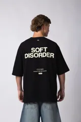 Remera de corte oversize color negro, confeccionada en algodón premium. Presenta un diseño gráfico minimalista estampado en el frente con tipografía y logotipos en color crema.